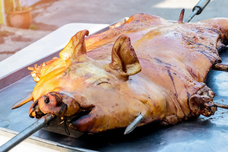 Whole roasted pig on a spit, similar to the kalua pig served at a luau