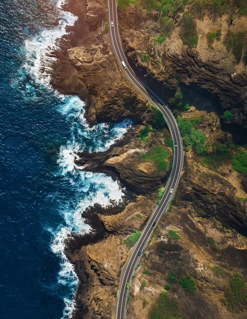Aerial view of a coastal highway winding above a rocky shoreline