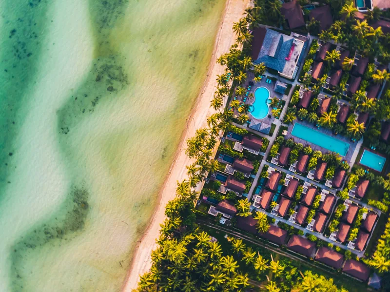 Aerial view of a beachfront resort with pools beside turquoise water