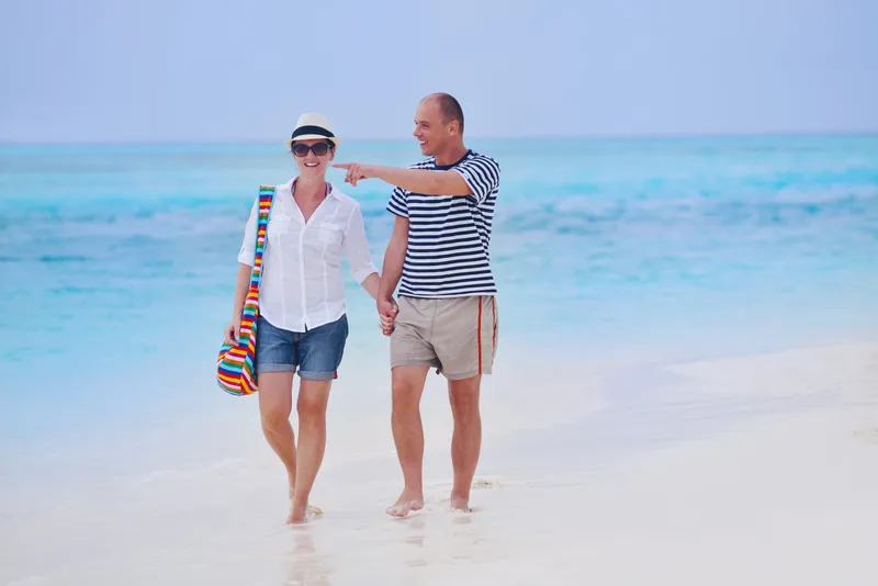 Couple in casual summer clothes walking on a tropical beach